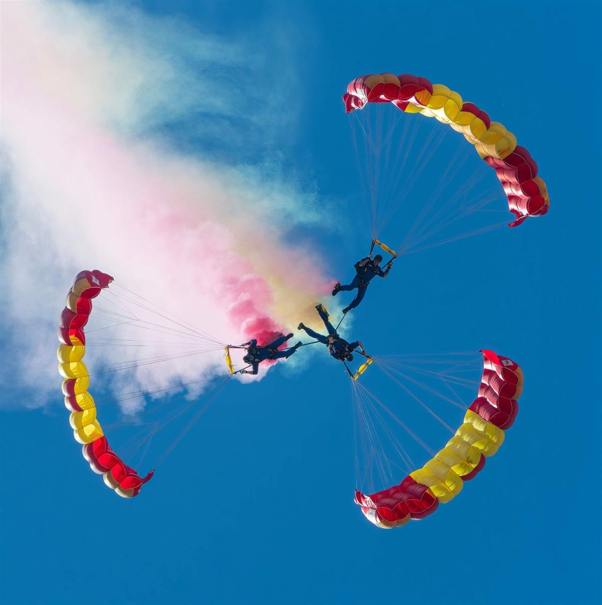 Dos paracaídas de colores con humo en el cielo