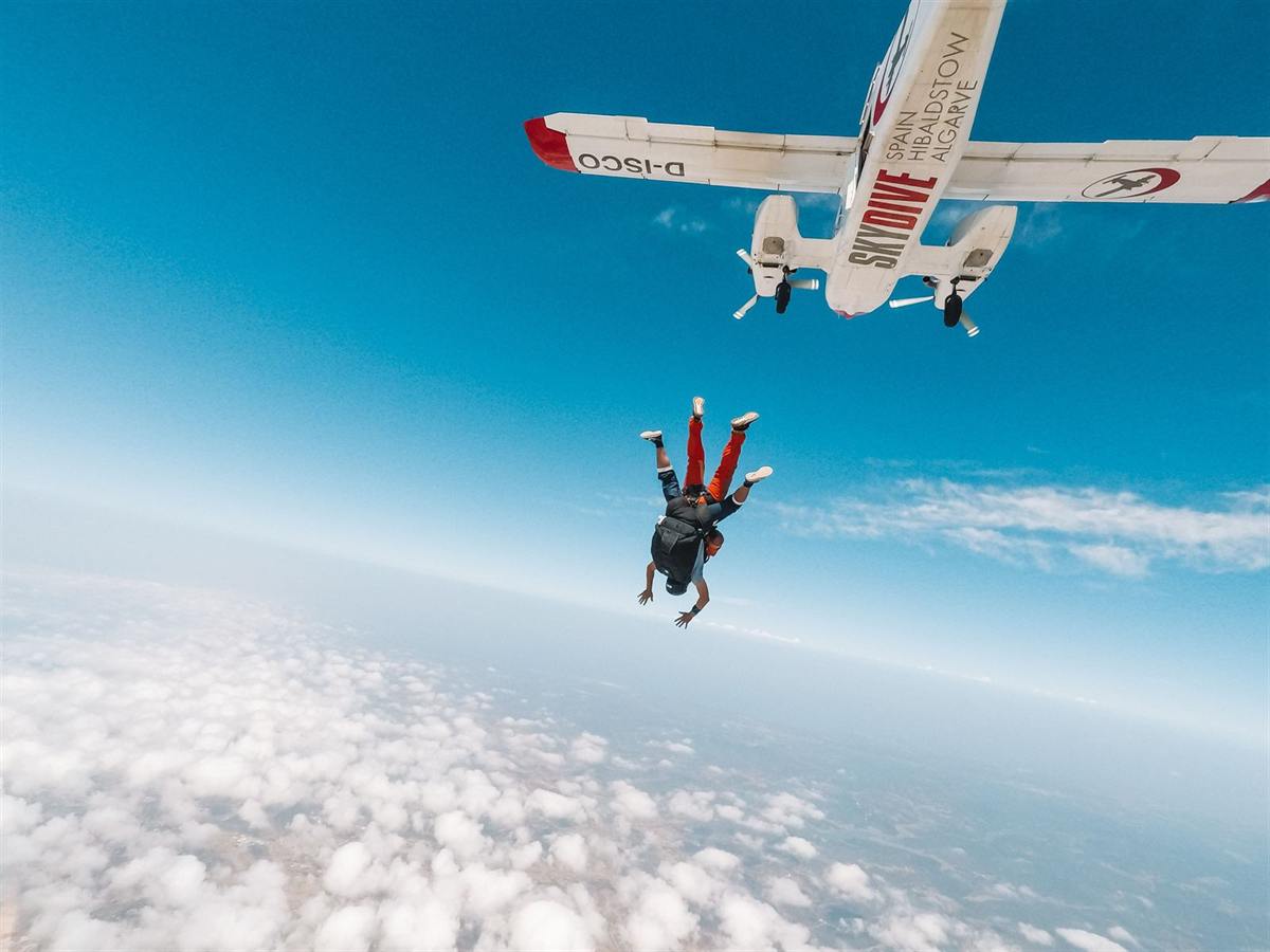 Paracaidista en caída libre bajo el avión, sobre las nubes