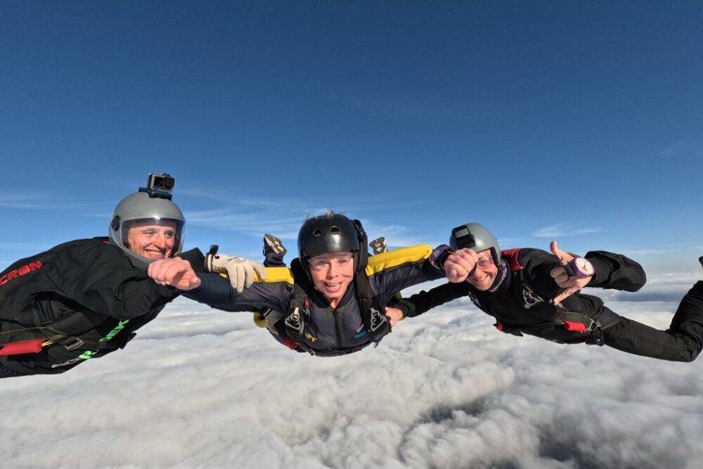 Tres paracaidistas en caída libre sobre las nubes